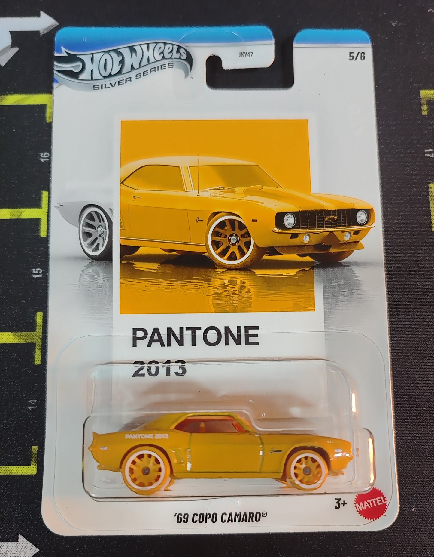 Hot Wheels '69 Copo Camaro toy car in Pantone 2013 packaging on a black background