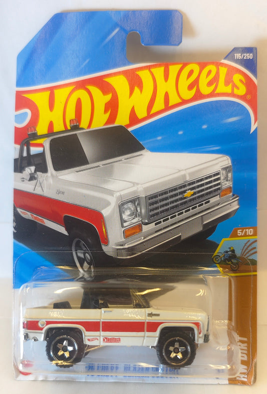 Hot Wheels Hot Wheels – '75 Chevy Blazer Custom (Mainline | HW Dirt Series | White with Red Stripe | 1:64 Scale Diecast) toy truck in packaging with blue and red design Front Pack