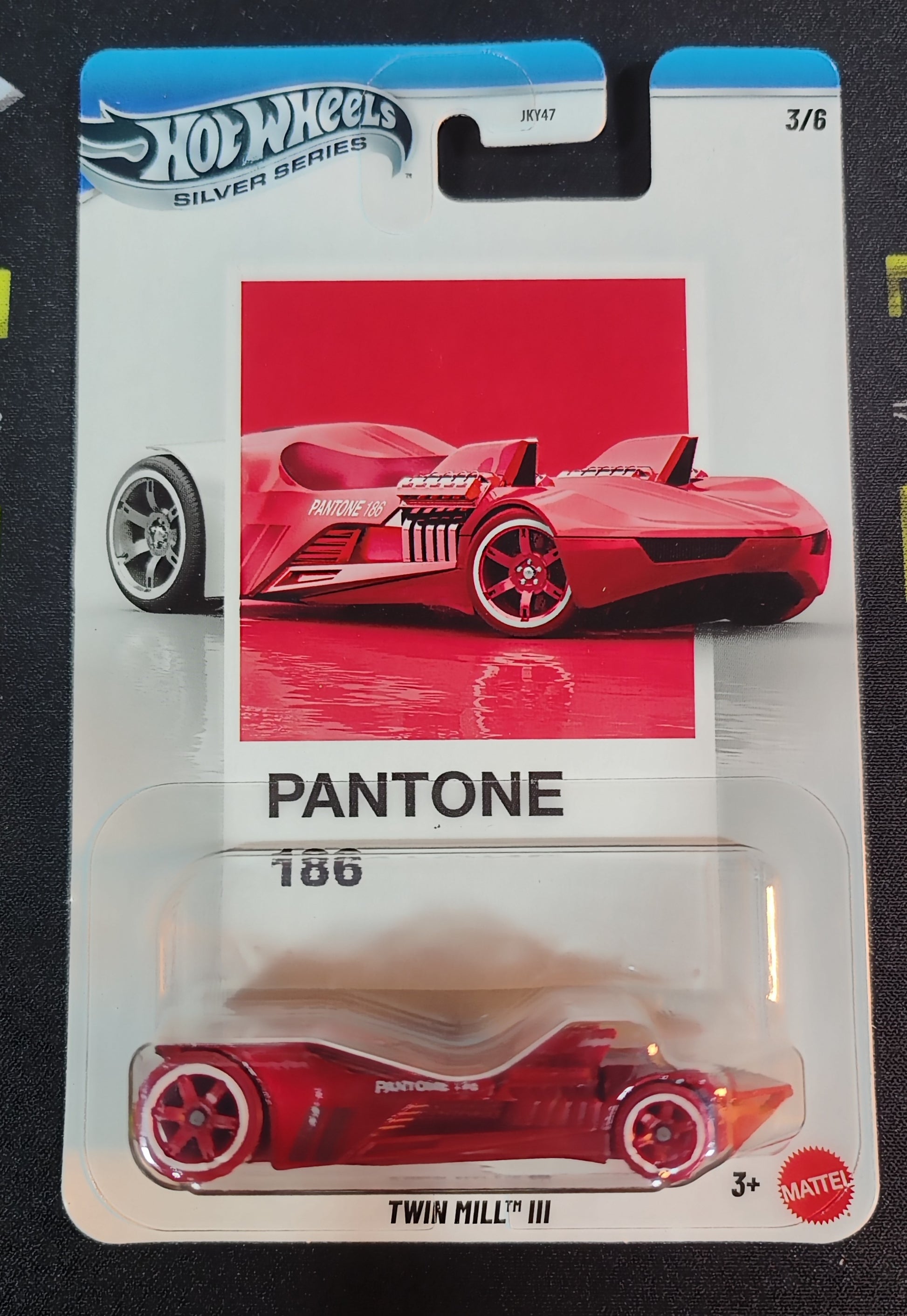 Hot Wheels toy car in Pantone 186 packaging on a black background