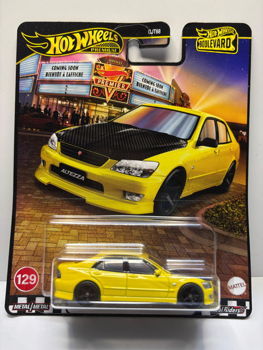 Hot Wheels yellow car model in packaging with a movie theater background